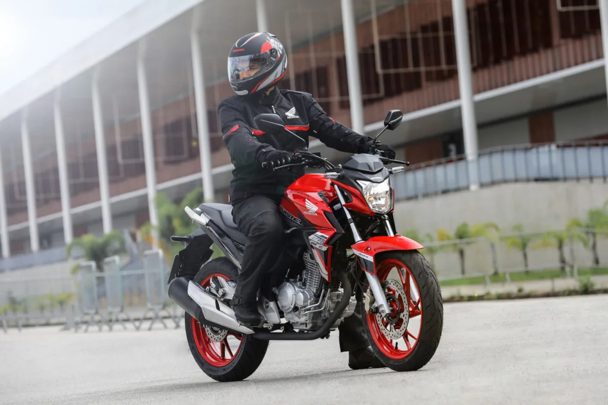 honda cb 250 twister 2021 vermelha sendo pilotada, visão frontal lateral direita