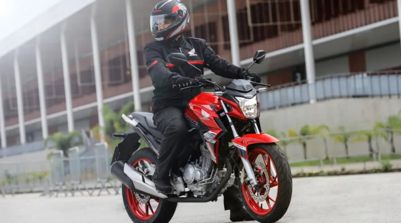 honda cb 250 twister 2021 vermelha sendo pilotada, visão frontal lateral direita